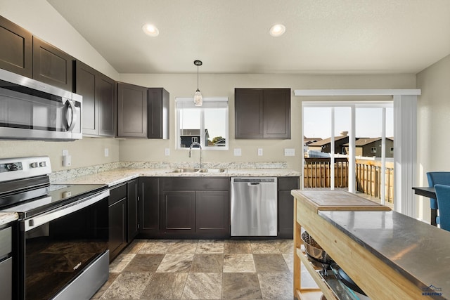 kitchen with dark brown cabinetry, sink, decorative light fixtures, appliances with stainless steel finishes, and vaulted ceiling