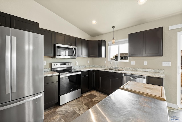 kitchen featuring light stone counters, hanging light fixtures, sink, appliances with stainless steel finishes, and vaulted ceiling