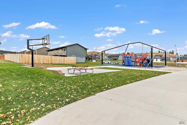 view of basketball court featuring a playground and a lawn