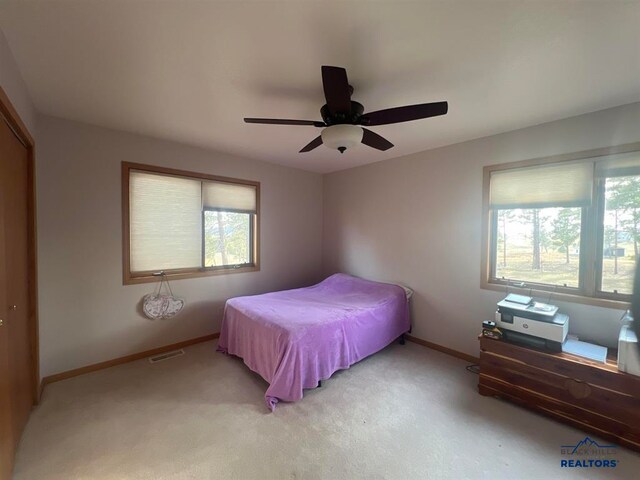 bedroom featuring ceiling fan, light colored carpet, and multiple windows