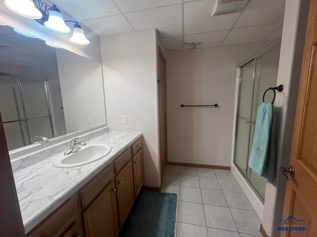 bathroom with vanity, a drop ceiling, an enclosed shower, and tile patterned floors