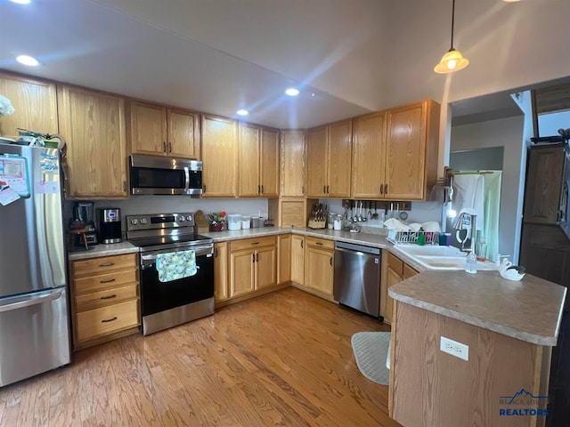 kitchen featuring kitchen peninsula, stainless steel appliances, light brown cabinetry, light hardwood / wood-style flooring, and decorative light fixtures