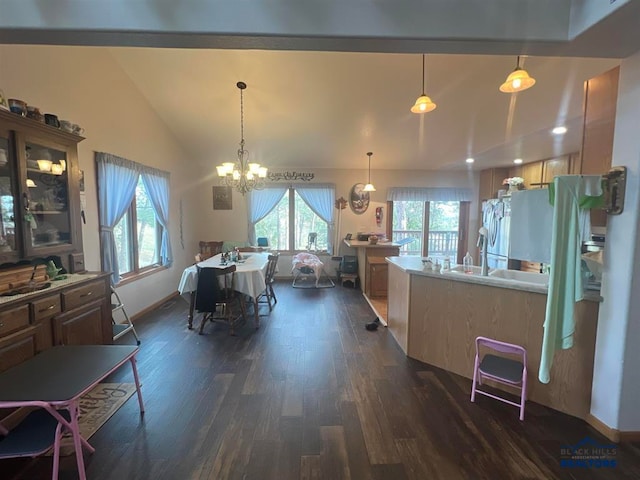 kitchen featuring stainless steel fridge, vaulted ceiling, dark wood-type flooring, pendant lighting, and an inviting chandelier