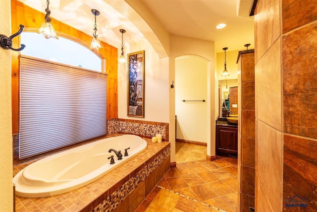 bathroom featuring tile patterned floors, a relaxing tiled tub, and vanity