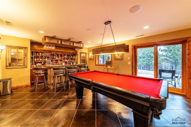 game room with dark tile patterned floors, bar, pool table, and plenty of natural light