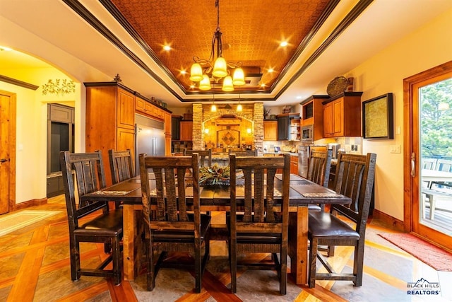 dining space featuring a notable chandelier, crown molding, and a tray ceiling