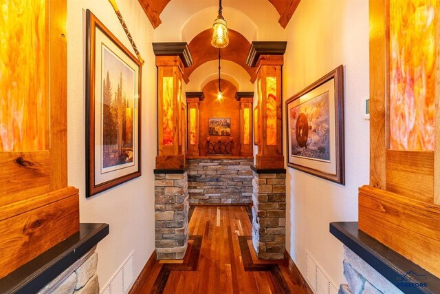 hallway featuring decorative columns and dark wood-type flooring