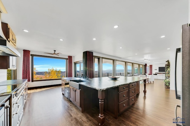 kitchen with a large island, hardwood / wood-style flooring, dark brown cabinetry, and sink