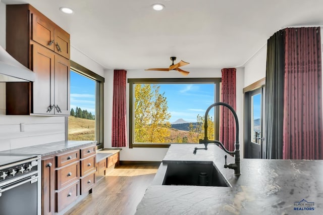 kitchen featuring ceiling fan, sink, light hardwood / wood-style floors, a mountain view, and electric stove