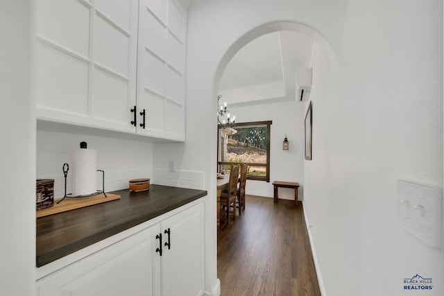 bar featuring white cabinets, an inviting chandelier, dark wood-type flooring, and butcher block counters