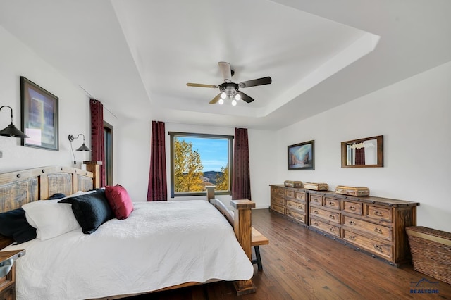 bedroom featuring ceiling fan, a raised ceiling, and dark hardwood / wood-style floors