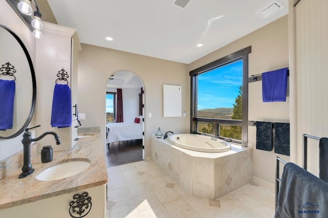 bathroom featuring a relaxing tiled tub and vanity