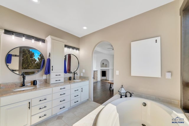 bathroom featuring ceiling fan, vanity, a bath, and hardwood / wood-style flooring