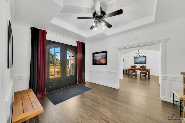 entryway featuring ceiling fan with notable chandelier, french doors, a tray ceiling, and hardwood / wood-style flooring