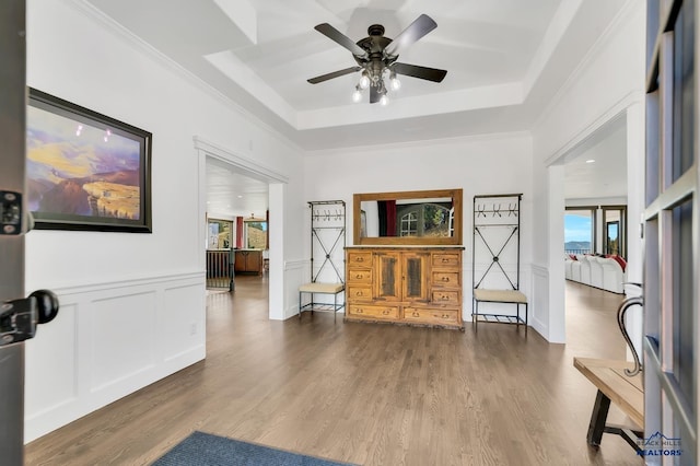 foyer with wood-type flooring, a raised ceiling, crown molding, and ceiling fan