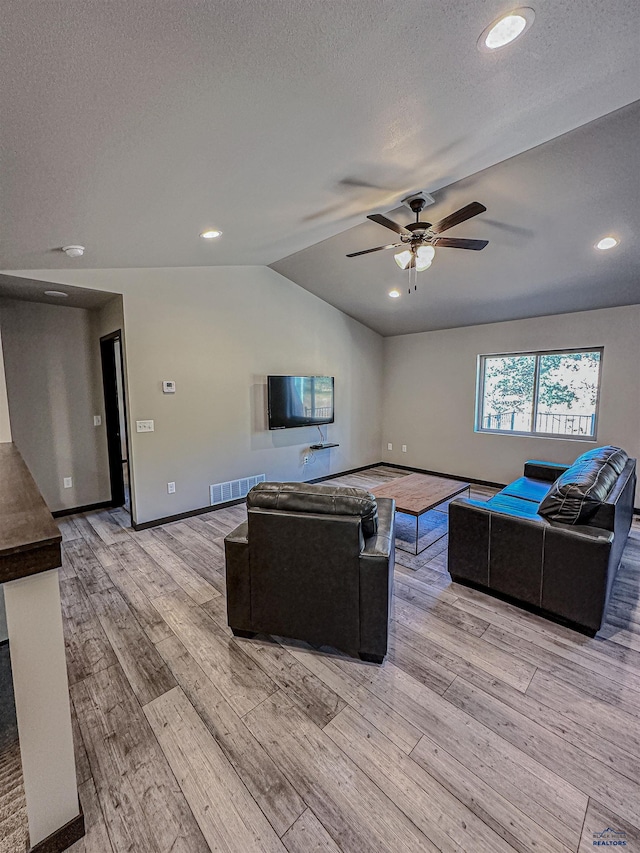 living room with lofted ceiling, ceiling fan, and light hardwood / wood-style floors