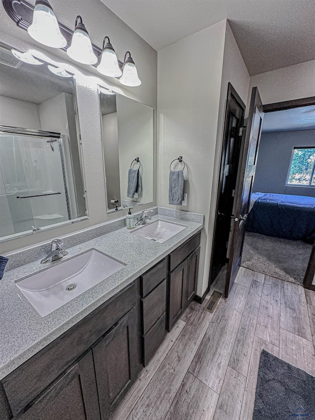 bathroom with hardwood / wood-style floors, a shower with door, vanity, and a textured ceiling