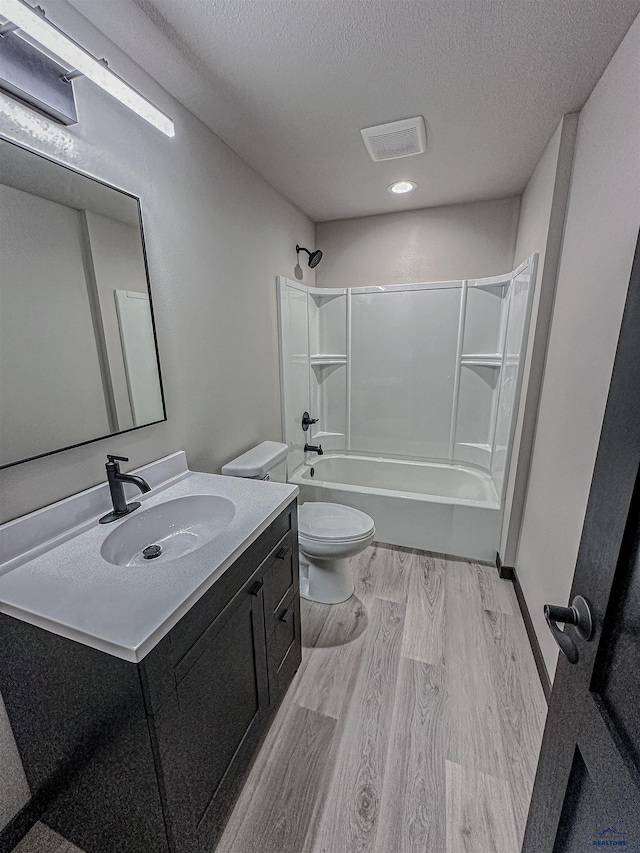 full bathroom with vanity, toilet, a textured ceiling, shower / tub combination, and hardwood / wood-style floors