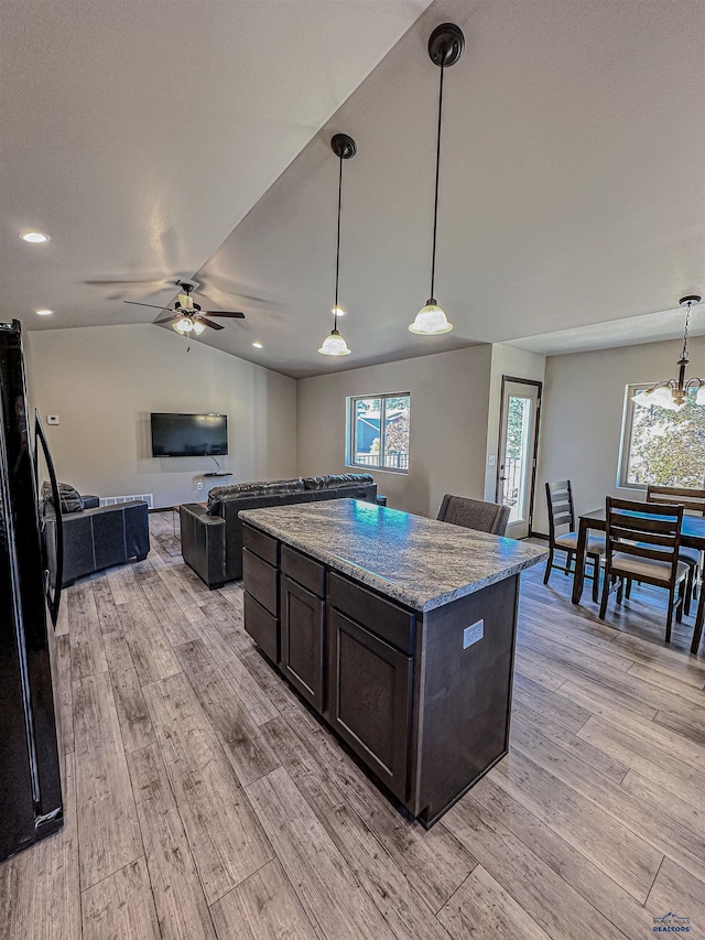 kitchen with lofted ceiling, light hardwood / wood-style flooring, decorative light fixtures, and light stone counters