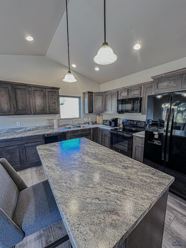 kitchen with lofted ceiling, black appliances, and light hardwood / wood-style floors