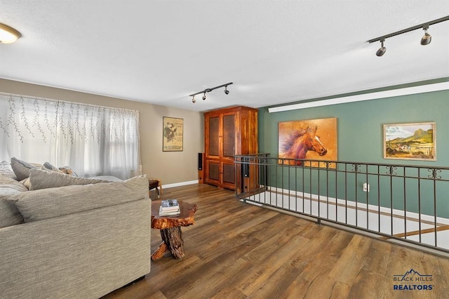 living room featuring track lighting, baseboards, and wood finished floors
