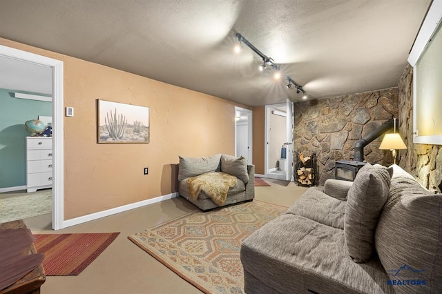 living area featuring baseboards, a textured ceiling, rail lighting, and a wood stove