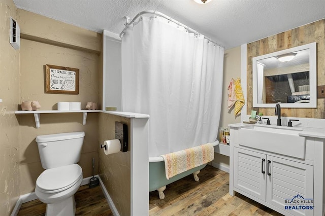 full bathroom featuring wood walls, a textured ceiling, hardwood / wood-style floors, toilet, and vanity