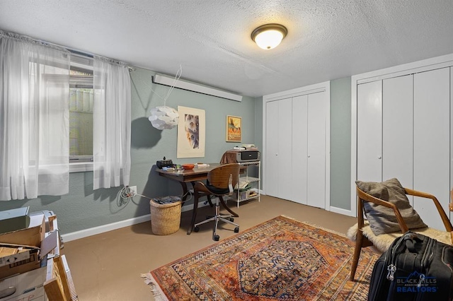office area featuring baseboards, a textured ceiling, and concrete floors