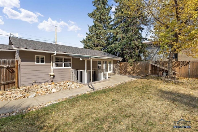 back of property featuring a yard, roof with shingles, a porch, and a fenced backyard