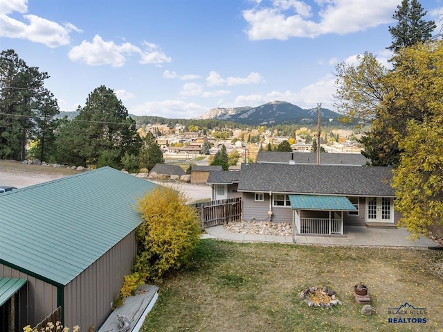 back of property with a mountain view, a lawn, and a patio area