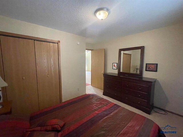 carpeted bedroom featuring a textured ceiling and a closet