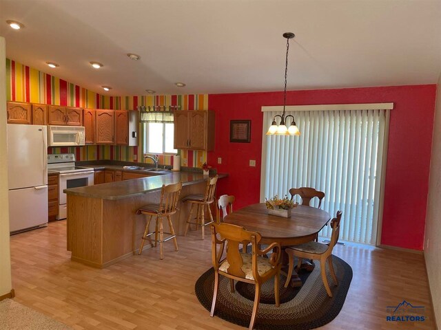 dining room with sink, light hardwood / wood-style flooring, and an inviting chandelier