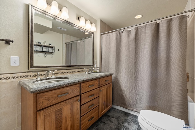 bathroom with curtained shower, a textured ceiling, toilet, tile walls, and vanity