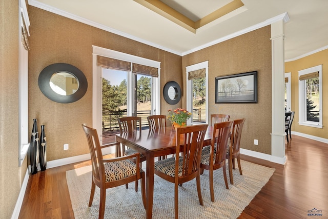 dining room featuring dark wood-type flooring, ornate columns, crown molding, and plenty of natural light