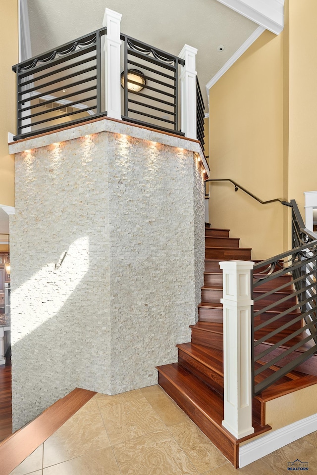 stairway with crown molding and tile patterned floors