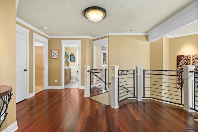 corridor featuring ornamental molding, a textured ceiling, and dark hardwood / wood-style floors