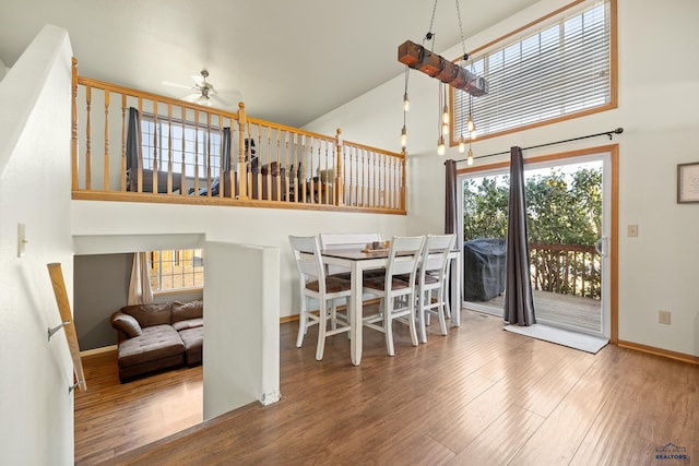 dining area featuring wood-type flooring, a high ceiling, and ceiling fan