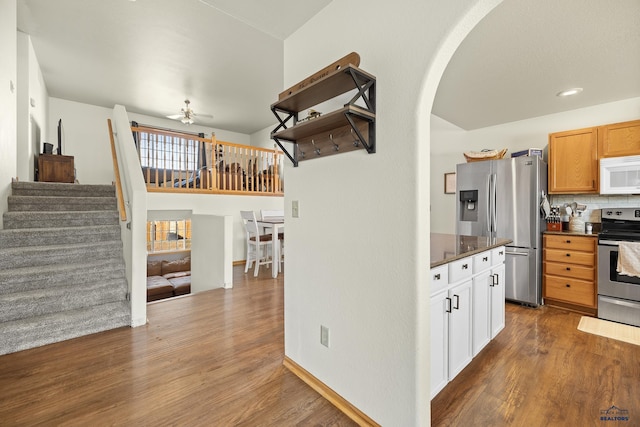 kitchen with white cabinets, tasteful backsplash, ceiling fan, appliances with stainless steel finishes, and wood-type flooring