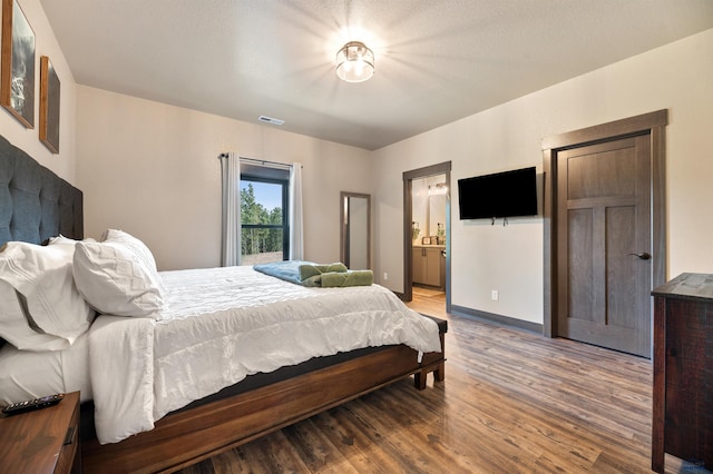 bedroom with ensuite bath and hardwood / wood-style flooring