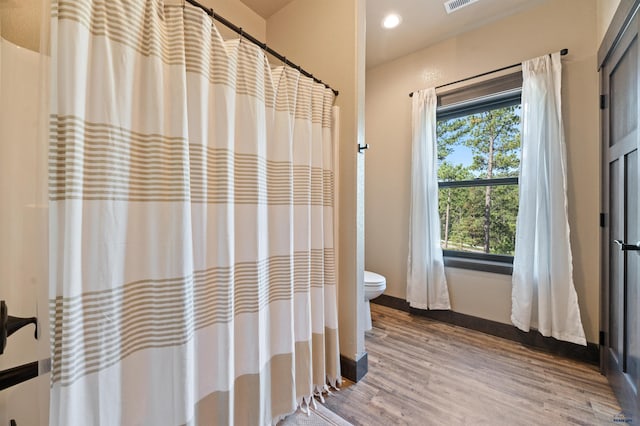 bathroom featuring toilet, walk in shower, and hardwood / wood-style floors