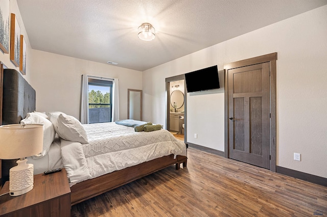 bedroom featuring ensuite bath, wood-type flooring, and a textured ceiling