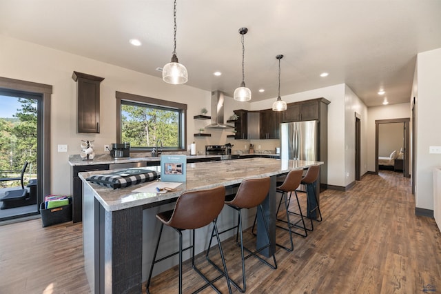 kitchen with a large island, hanging light fixtures, dark hardwood / wood-style flooring, dark brown cabinetry, and ventilation hood