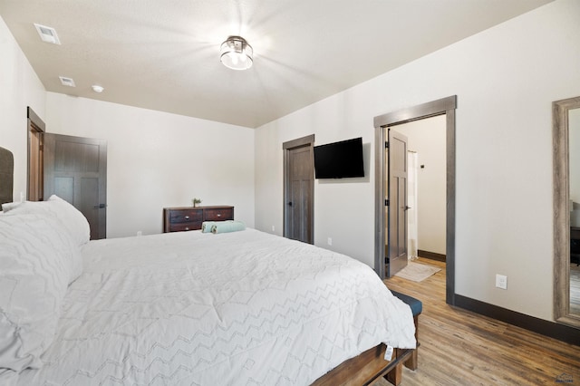 bedroom featuring ensuite bath and hardwood / wood-style flooring