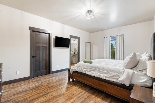 bedroom featuring ensuite bathroom and hardwood / wood-style flooring