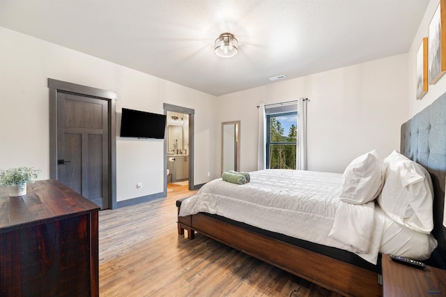 bedroom with light hardwood / wood-style floors and ensuite bath