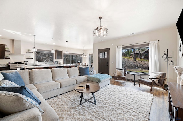 living room featuring light hardwood / wood-style flooring, sink, and a notable chandelier