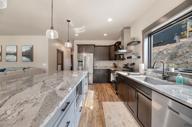 kitchen with dark brown cabinets, sink, light stone countertops, pendant lighting, and appliances with stainless steel finishes