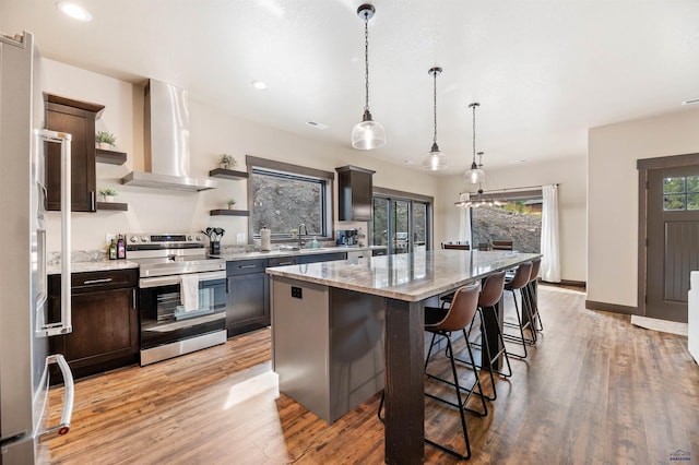 kitchen featuring stainless steel electric stove, a kitchen island, extractor fan, light hardwood / wood-style flooring, and pendant lighting