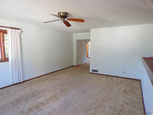 empty room featuring ceiling fan, light carpet, and a textured ceiling