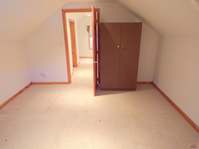 bonus room with light colored carpet and vaulted ceiling